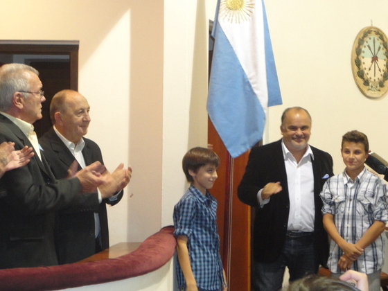 Izando la bandera, junto a Carlos Comi, los nietos de Solari, cuarta generación familiar.
