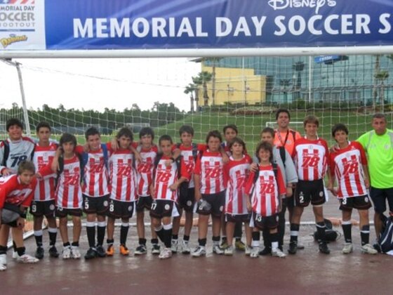 El Sub13 posando con su técnico y el coordinador Pisani, debajo de una bandera con el nombre del torneo.