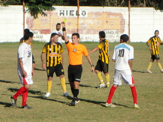 El árbitro Macheroni muestra una amarilla. Las expulsiones fueron determinantes.