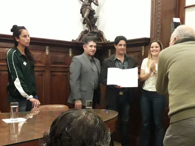 El Presidente de Social Lux, Pablo Montero, recibe la plaqueta que distingue a su institución. A su derecha, con la campera de Mercadito, la arquera de la Selección, Vanina Correa.